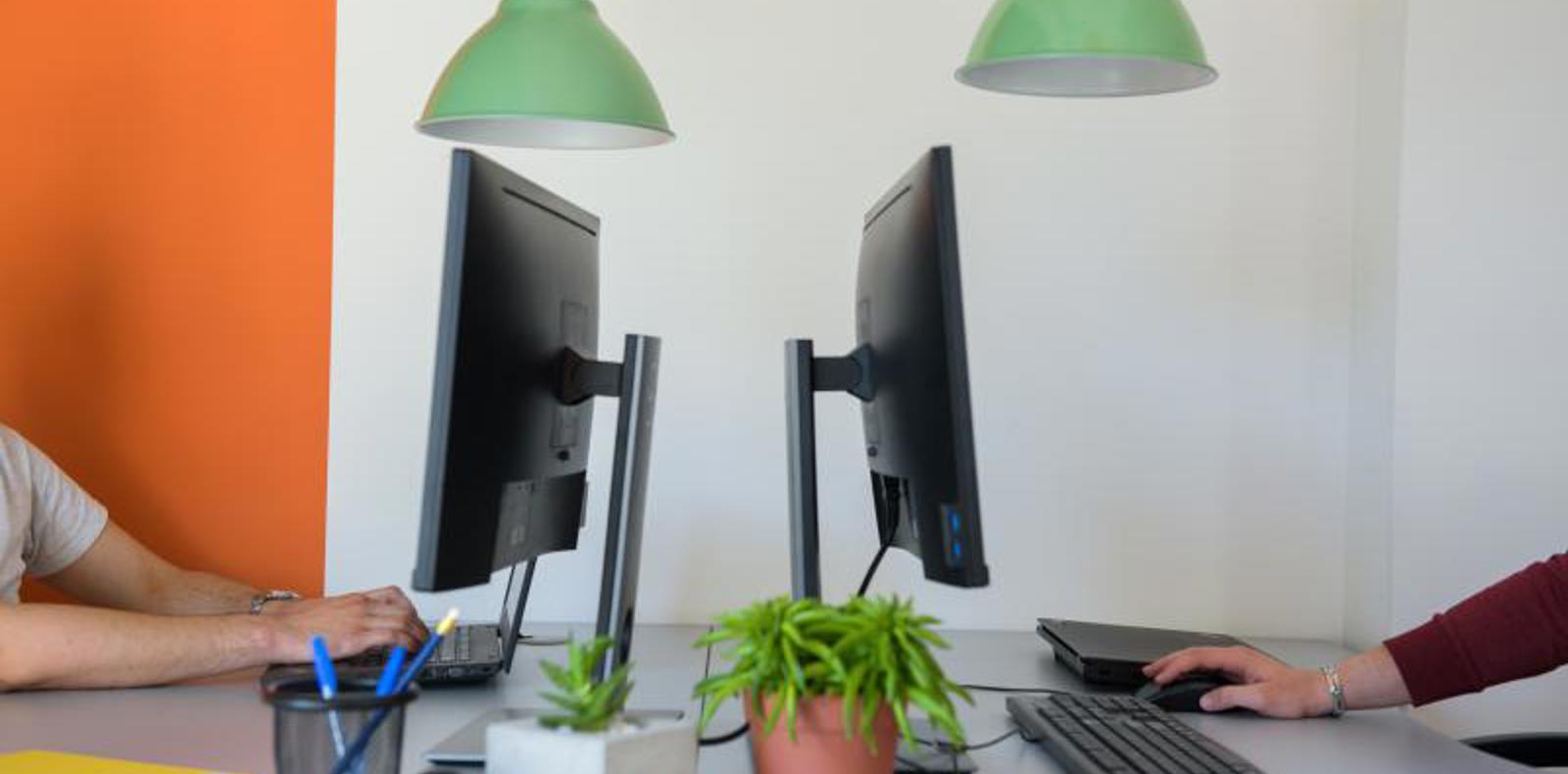 Two people working on computers at a desk.