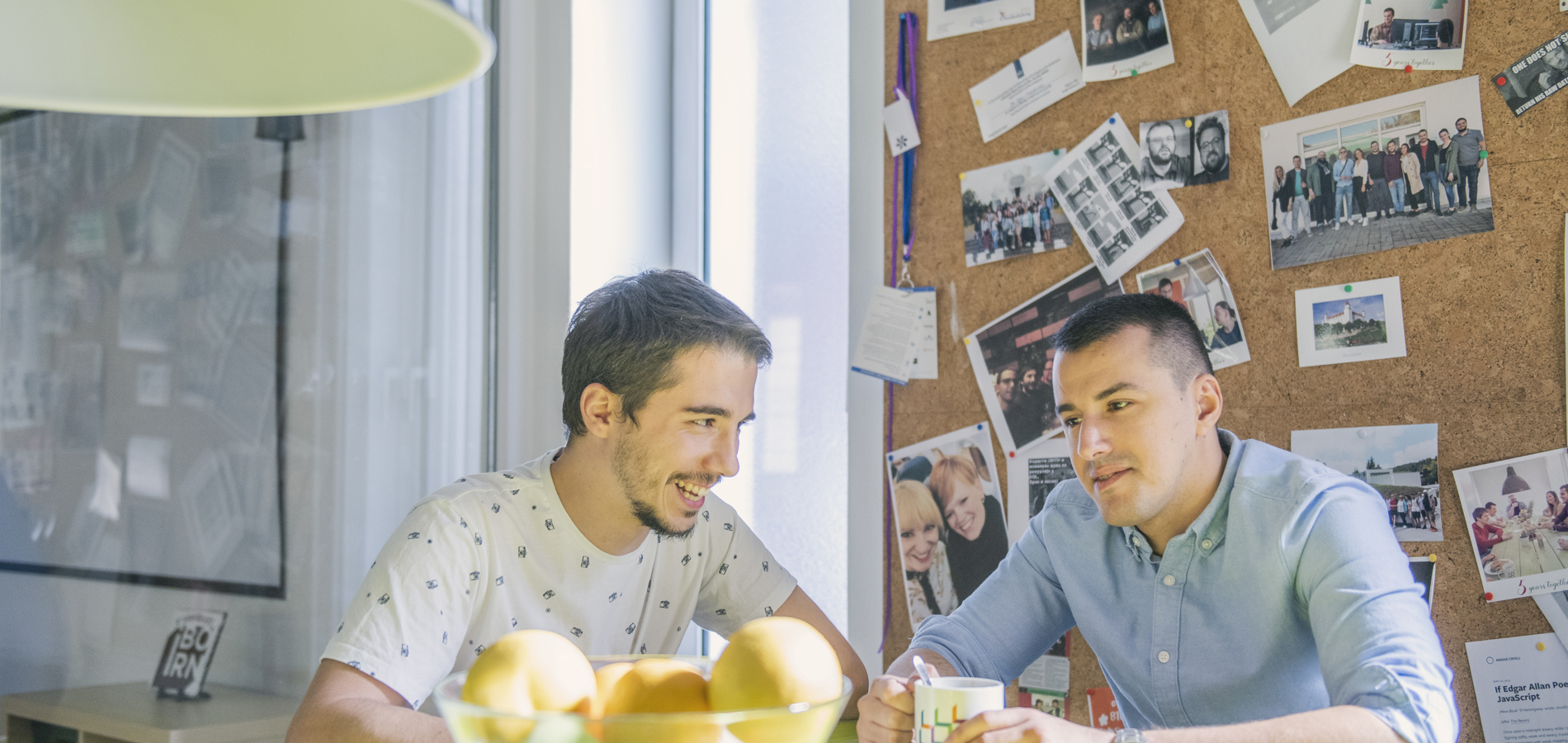 Two individuals having a discussion over a coffee in a bright sunny room.