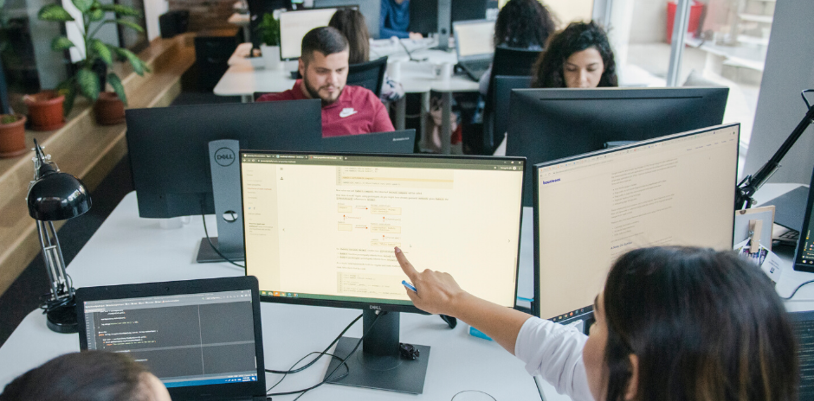 People working on computers in a modern office, collaborating and focusing on their tasks.