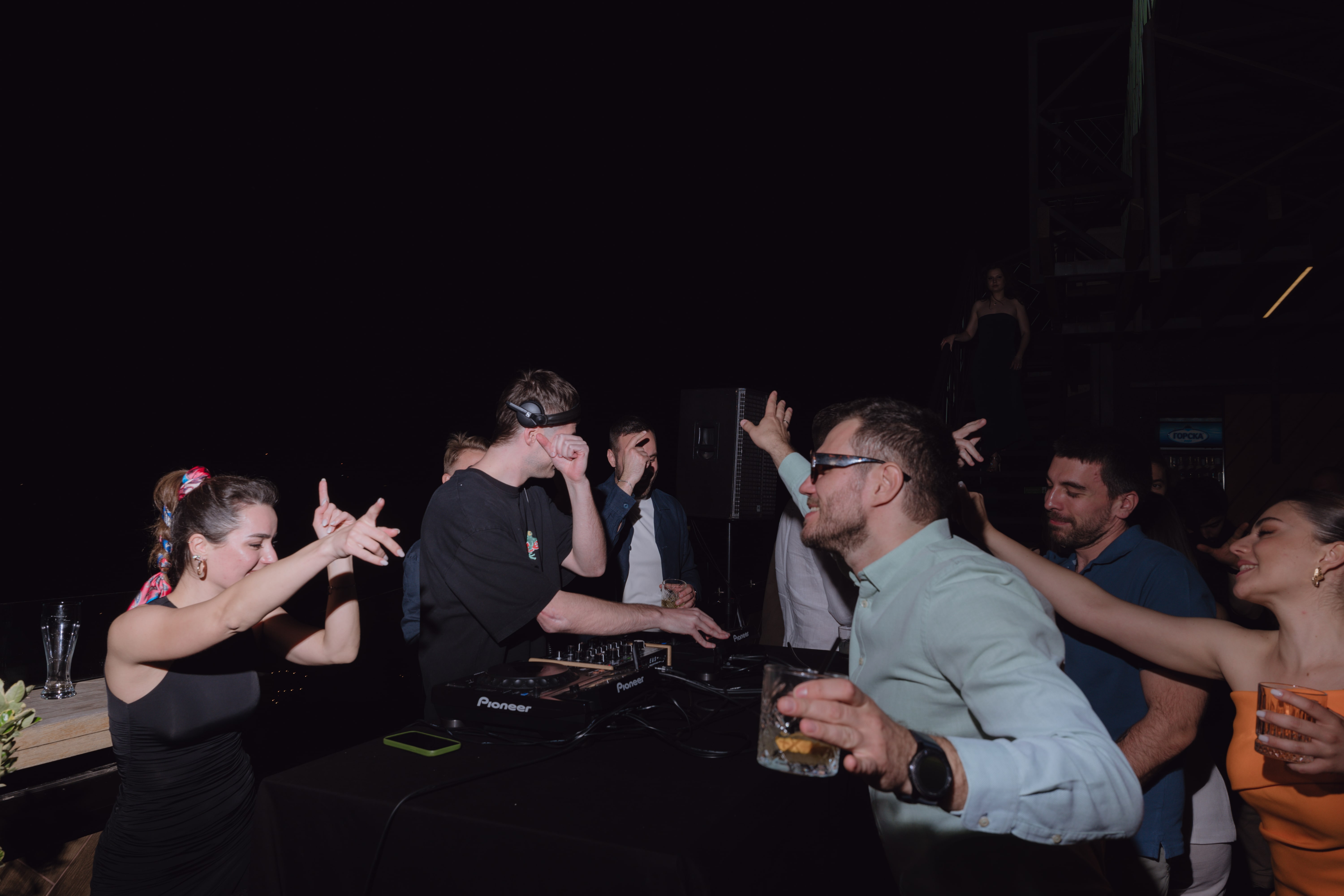 A lively party scene with people dancing and a DJ playing music.