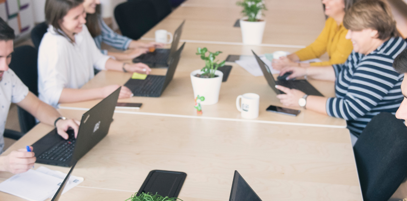 A team of professionals working together at a table, using laptops to accomplish tasks.