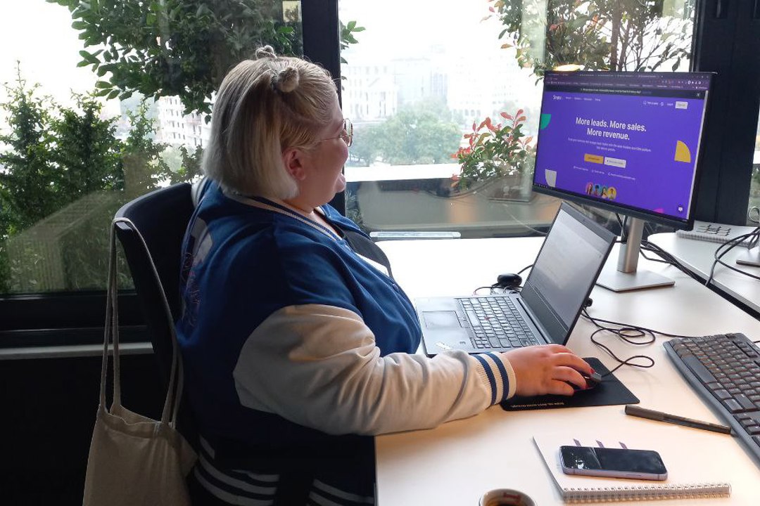 A woman focused on her work, sitting at a desk and using a laptop computer to get things done efficiently.