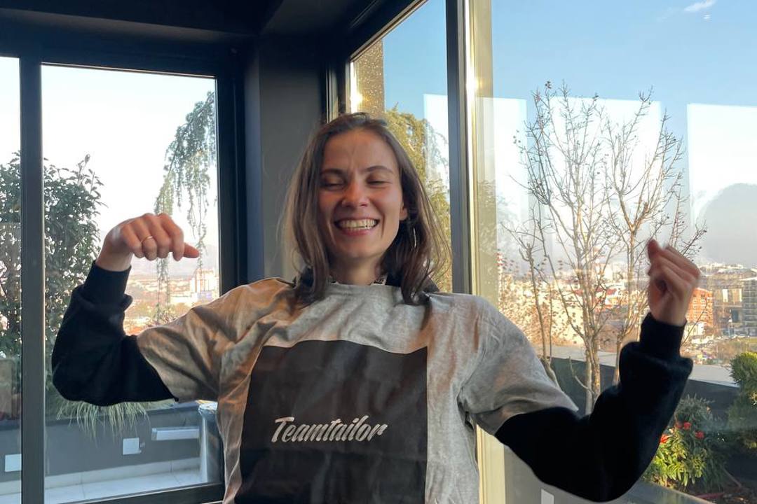 A woman in a grey Teamtailor t-shirt smiling for a photo.