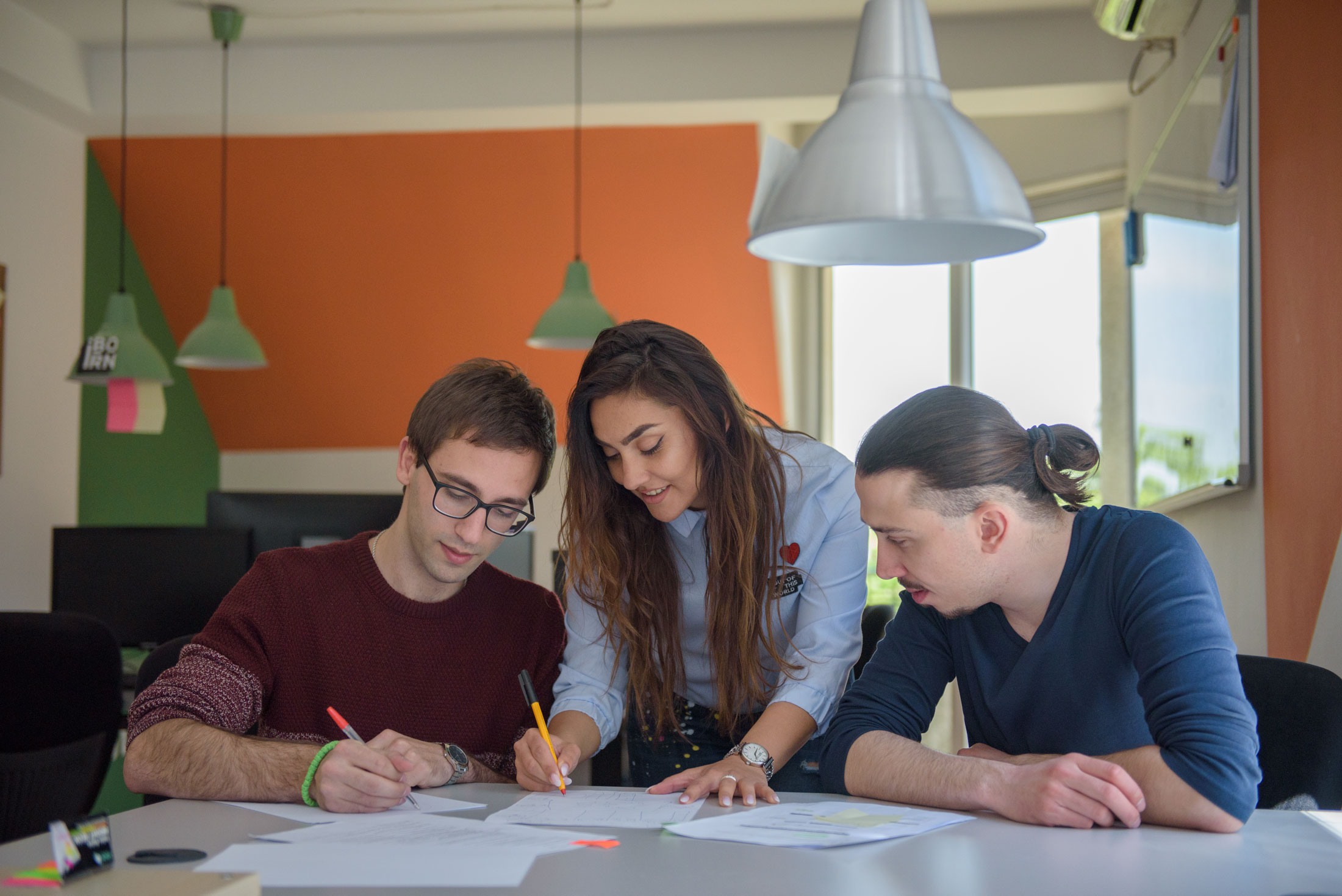 Three individuals collaborate in an office setting.