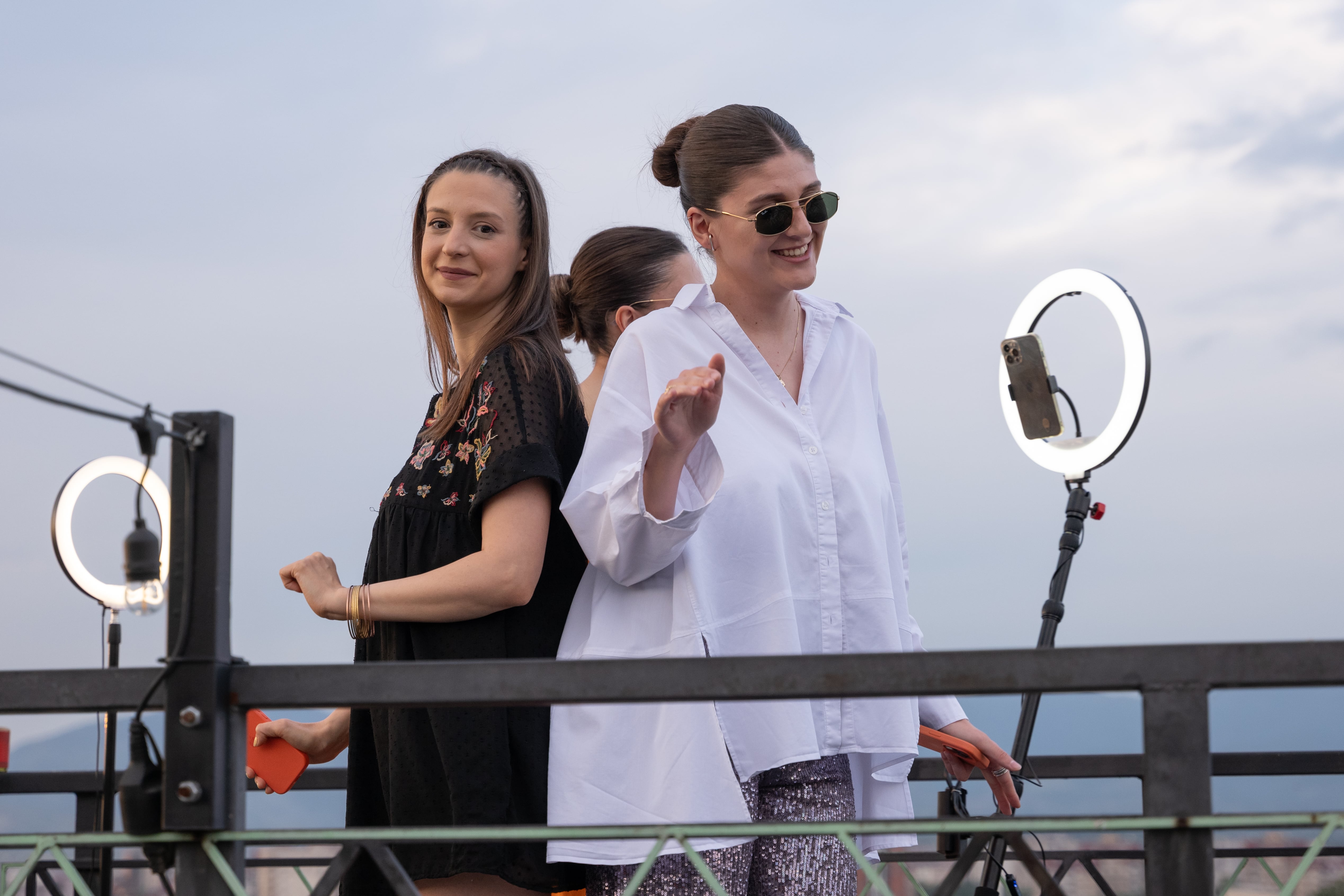 Women on a balcony, capturing a moment with a spin camera.

