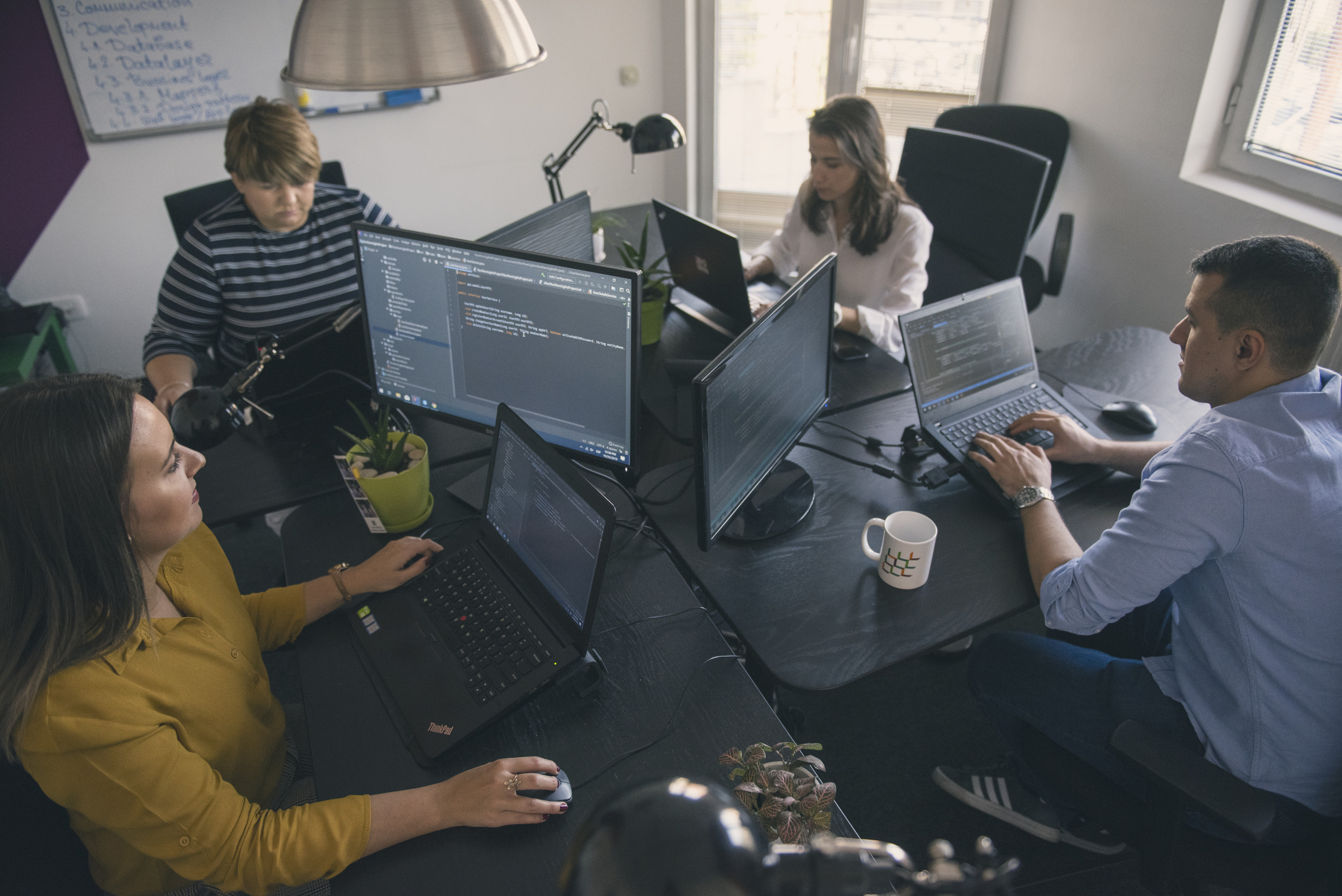 Employees focused on their work at computers in an office space.