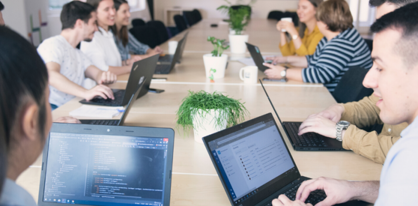 A team of professionals sitting at a table with laptops, likely discussing work or projects.