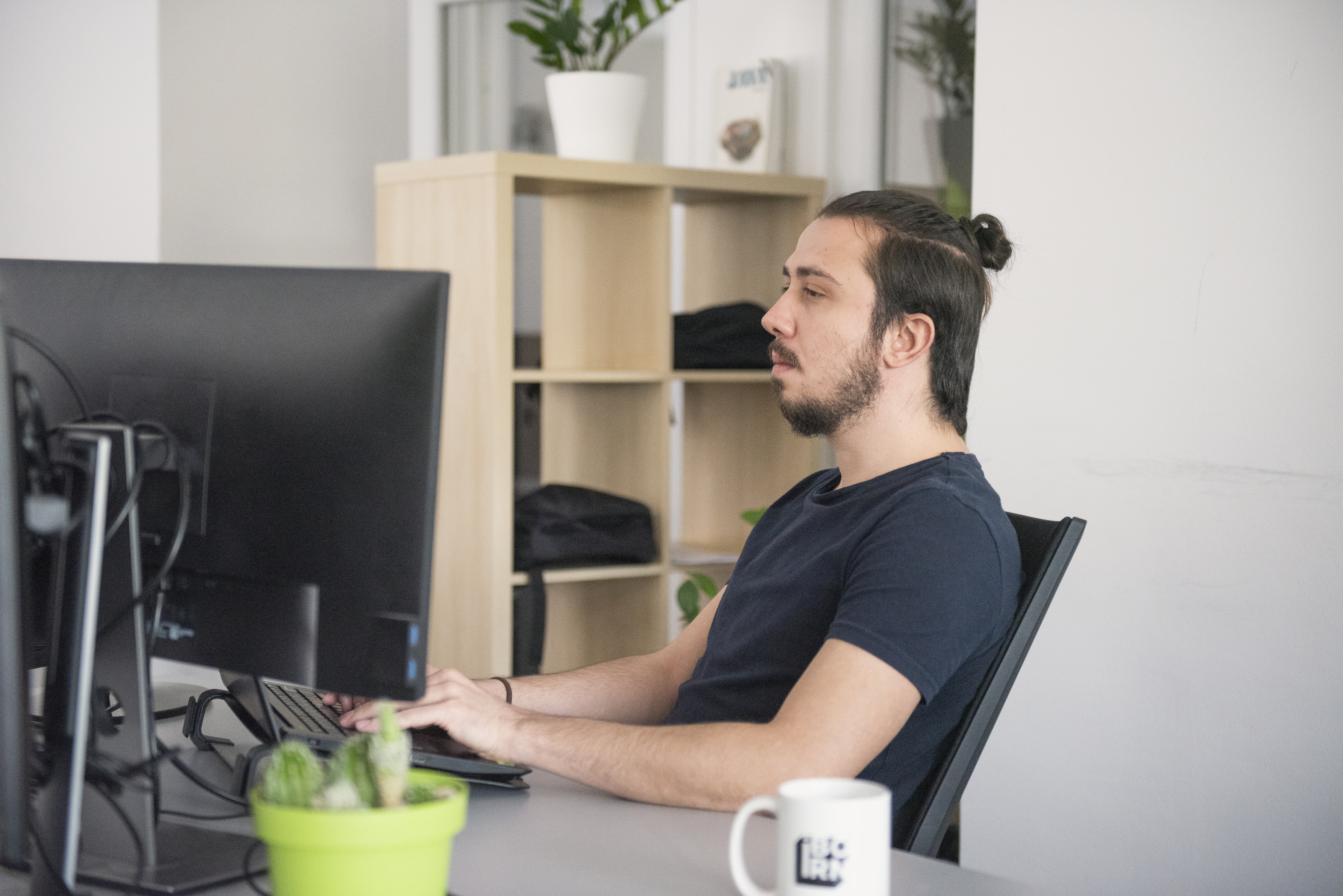 Software engineer working on a laptop in a modern office environment.