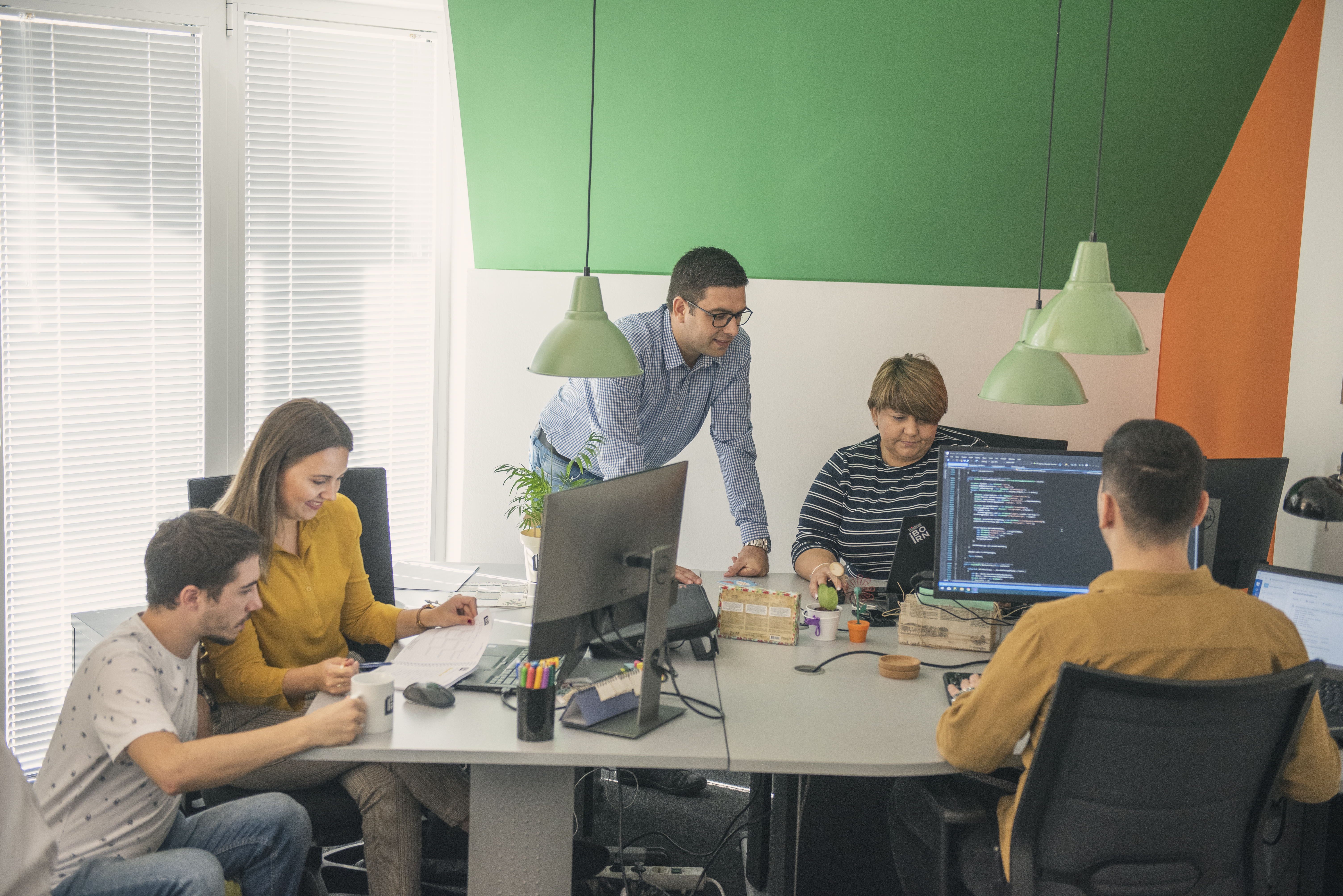 A team of professionals collaborating at a desk in an office, brainstorming and working together to achieve their goals.
