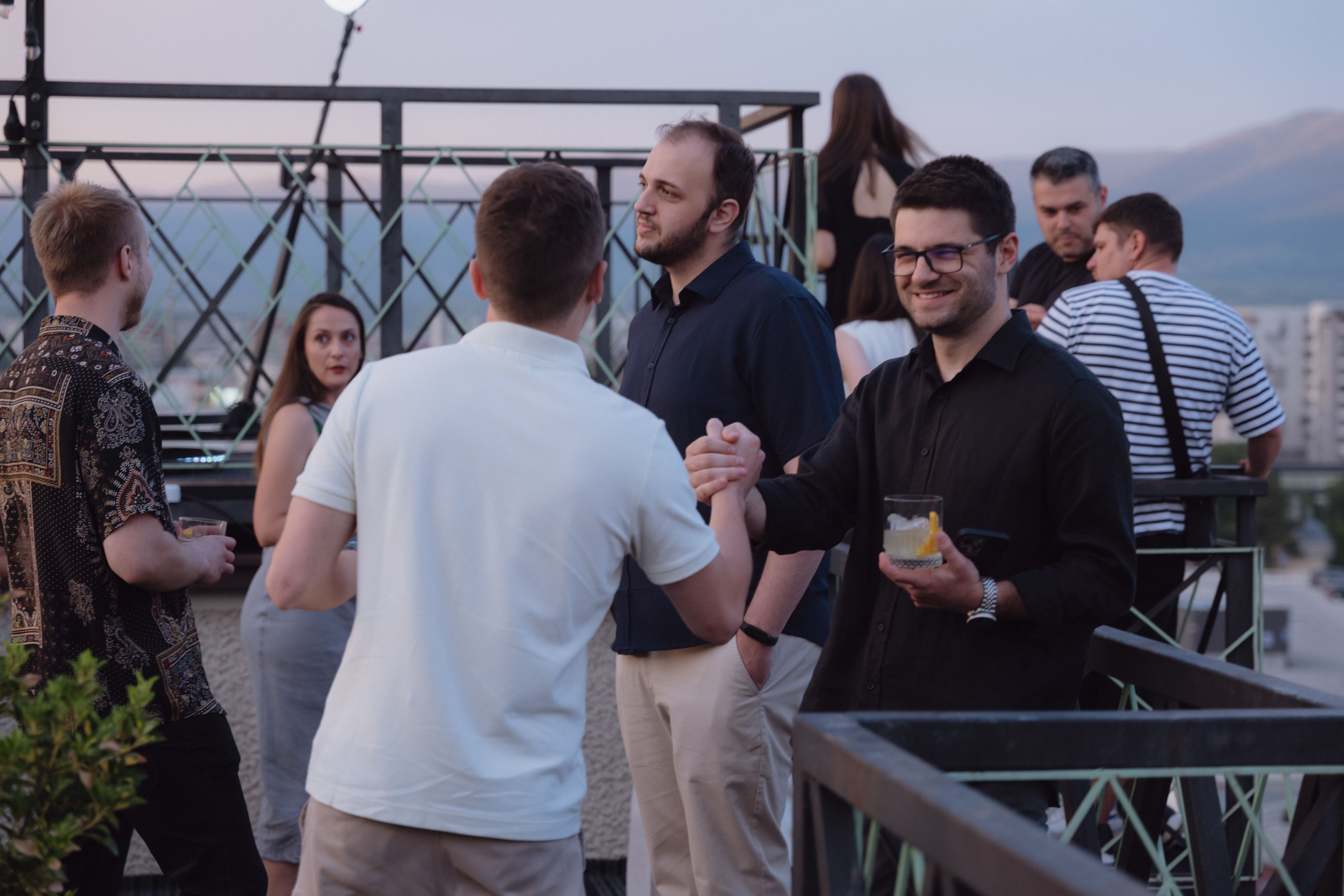 People enjoying drinks on a rooftop terrace with a stunning cityscape view.