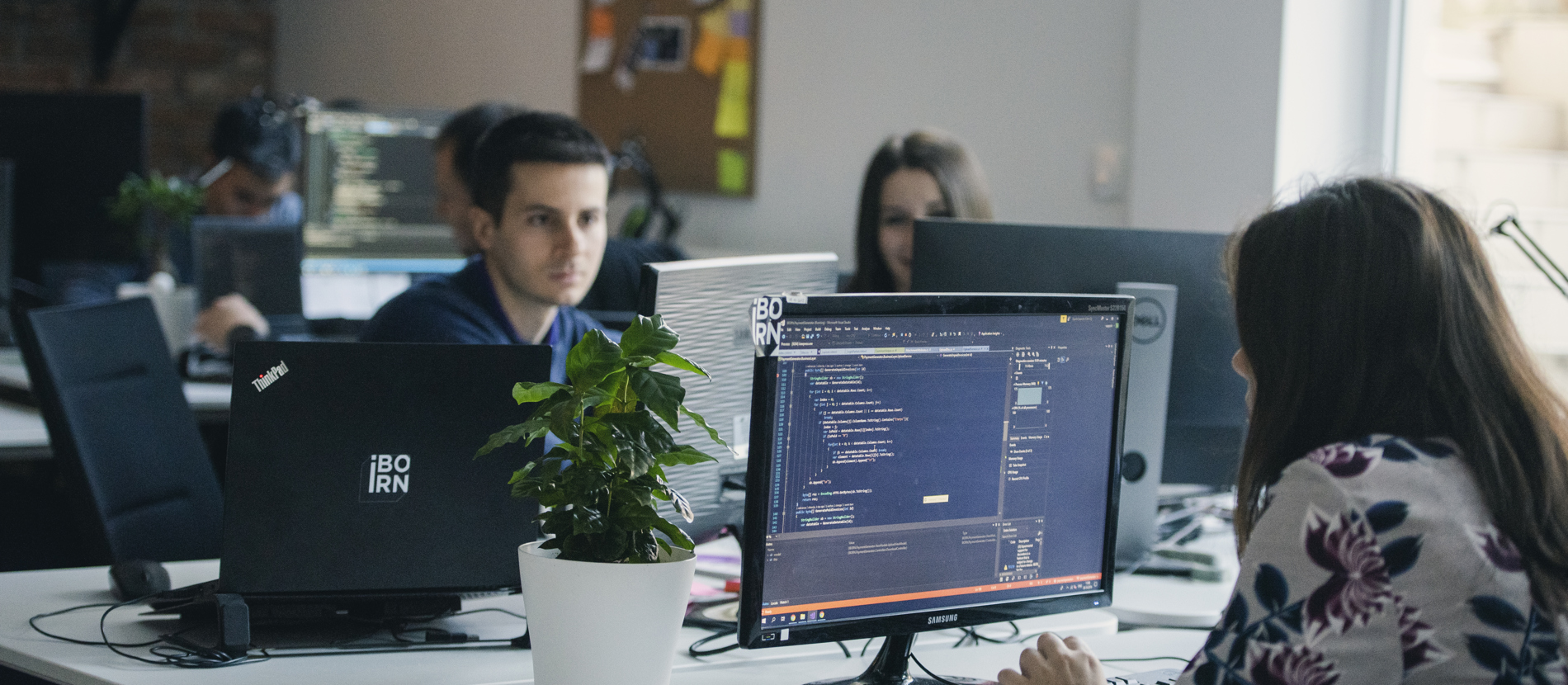 Three individuals collaborate in an office setting.