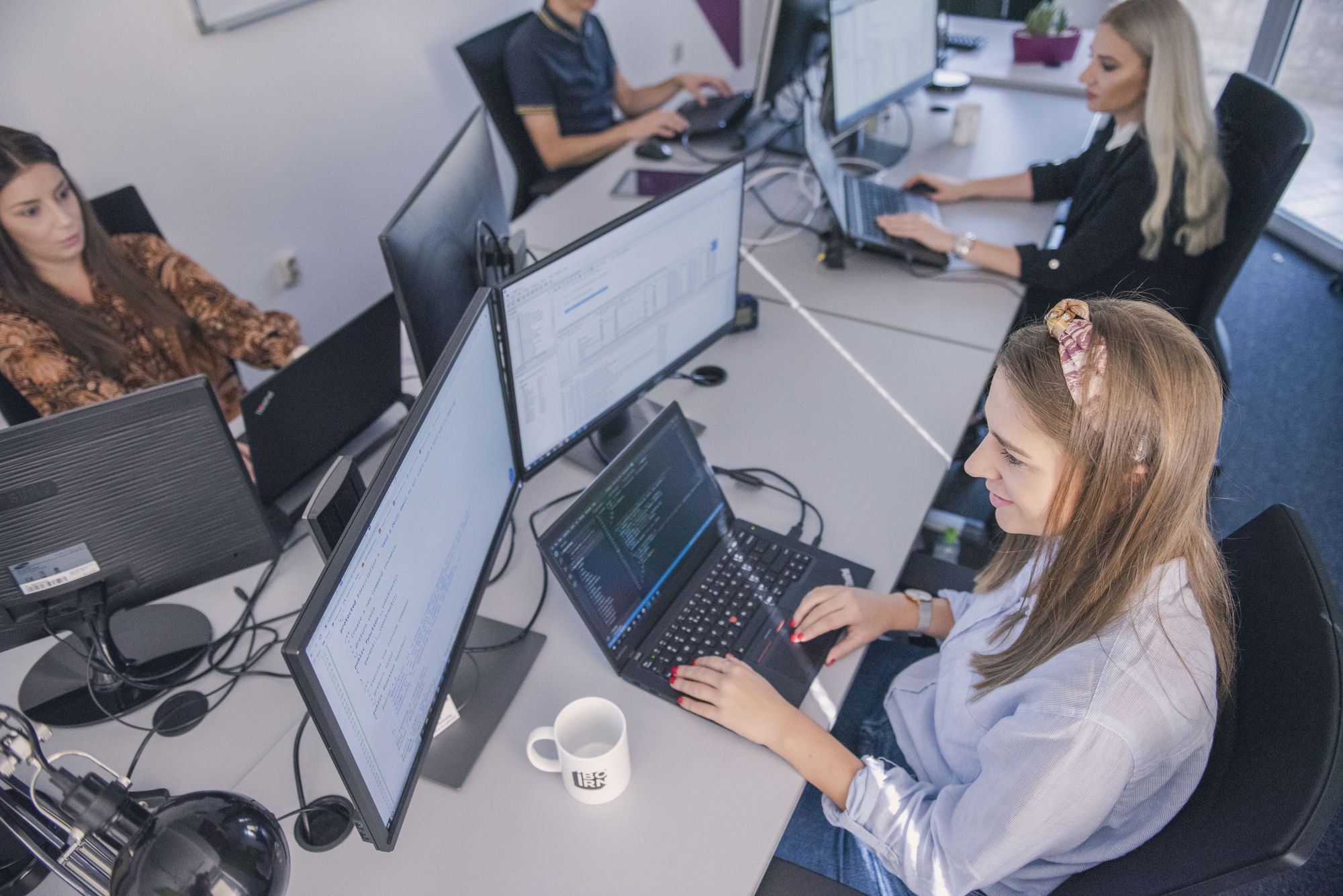 Software engineers working on their laptops in a modern office environment. 