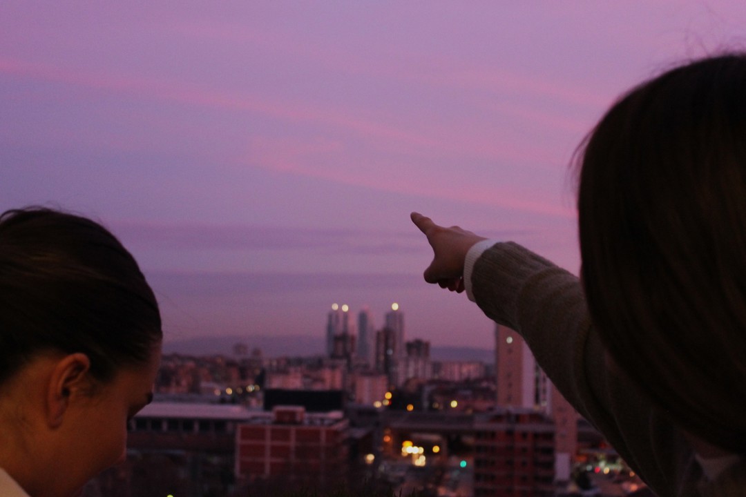 A woman pointing towards a beautiful sunset seen from the IBORN's headquarters 