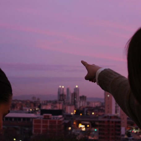 A woman pointing towards a beautiful sunset seen from the IBORN's headquarters