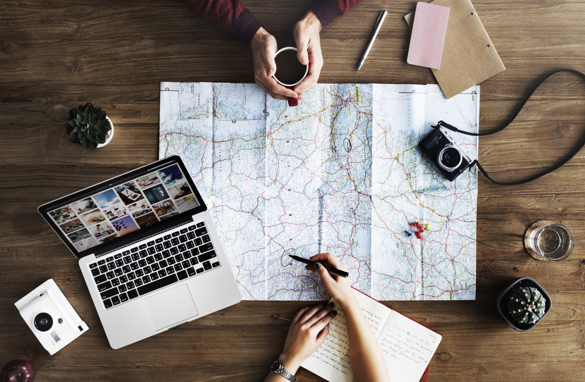 Two people with a laptop and a map, exploring new places and discussing over coffee where to travel. 