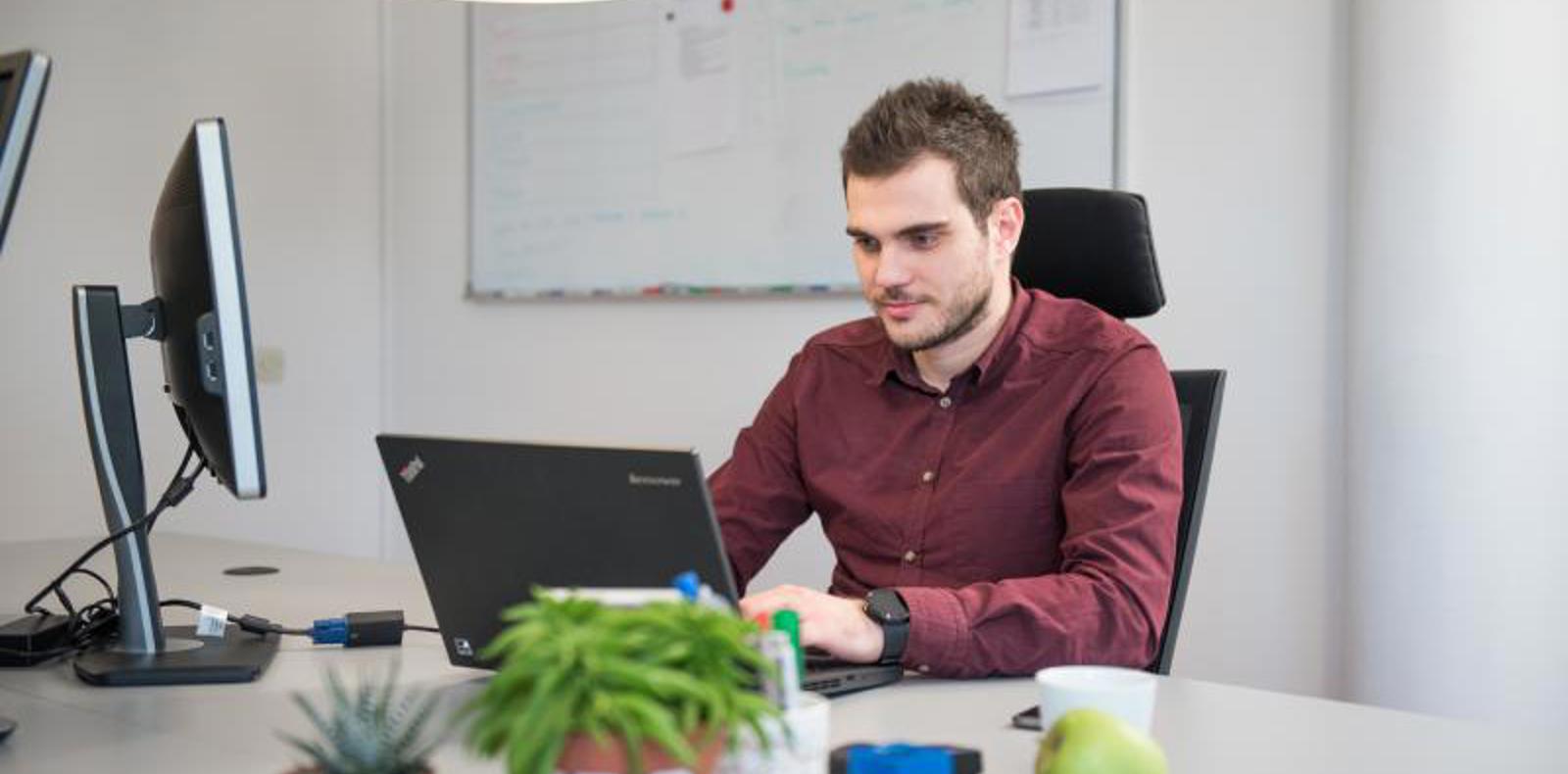 A man working on a laptop at a desk.