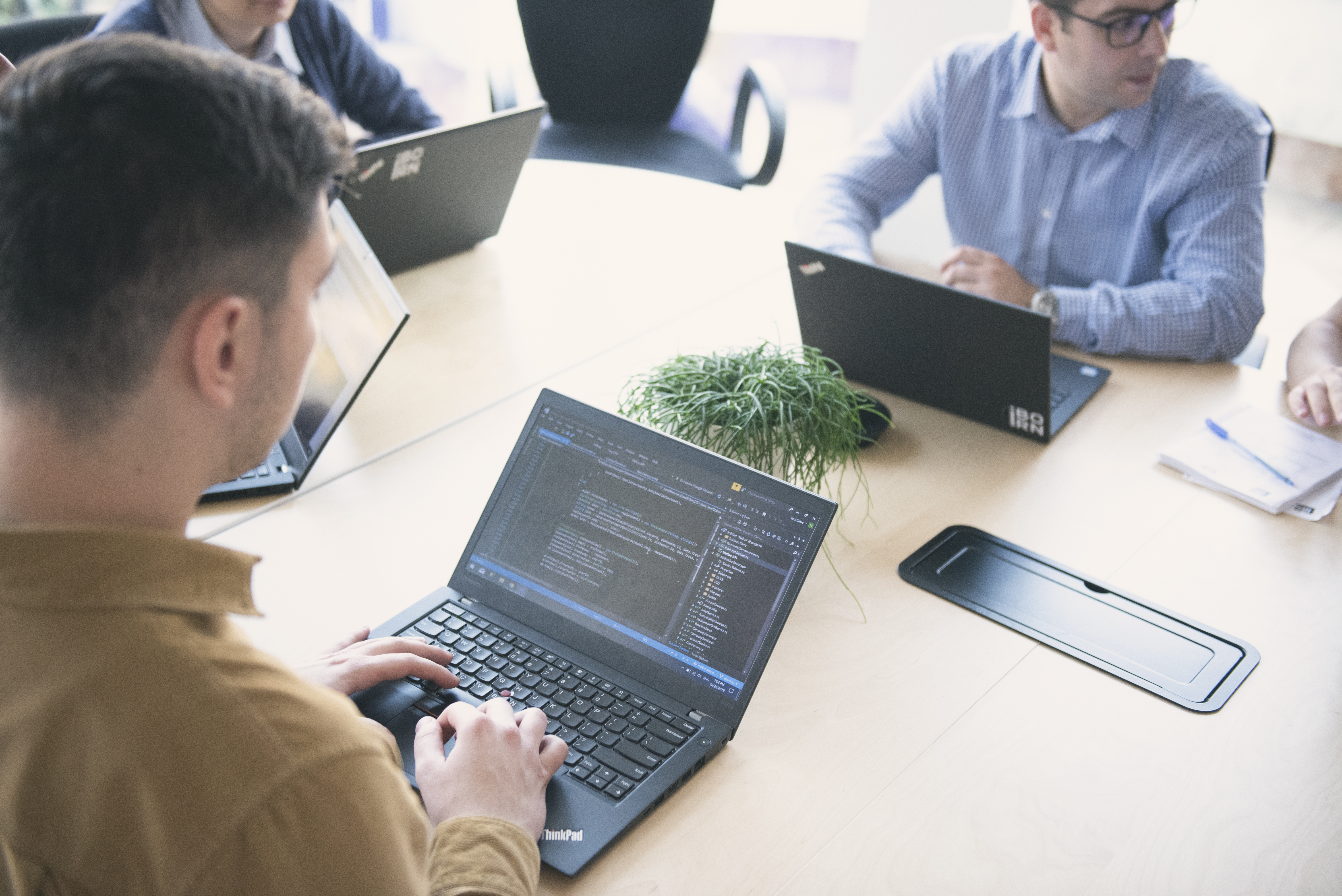 A  group of professionals collaborating on laptops in a well-lit meeting room.