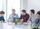 A diverse group of individuals sitting around a table with laptops, engaged in a meeting or collaboration session.