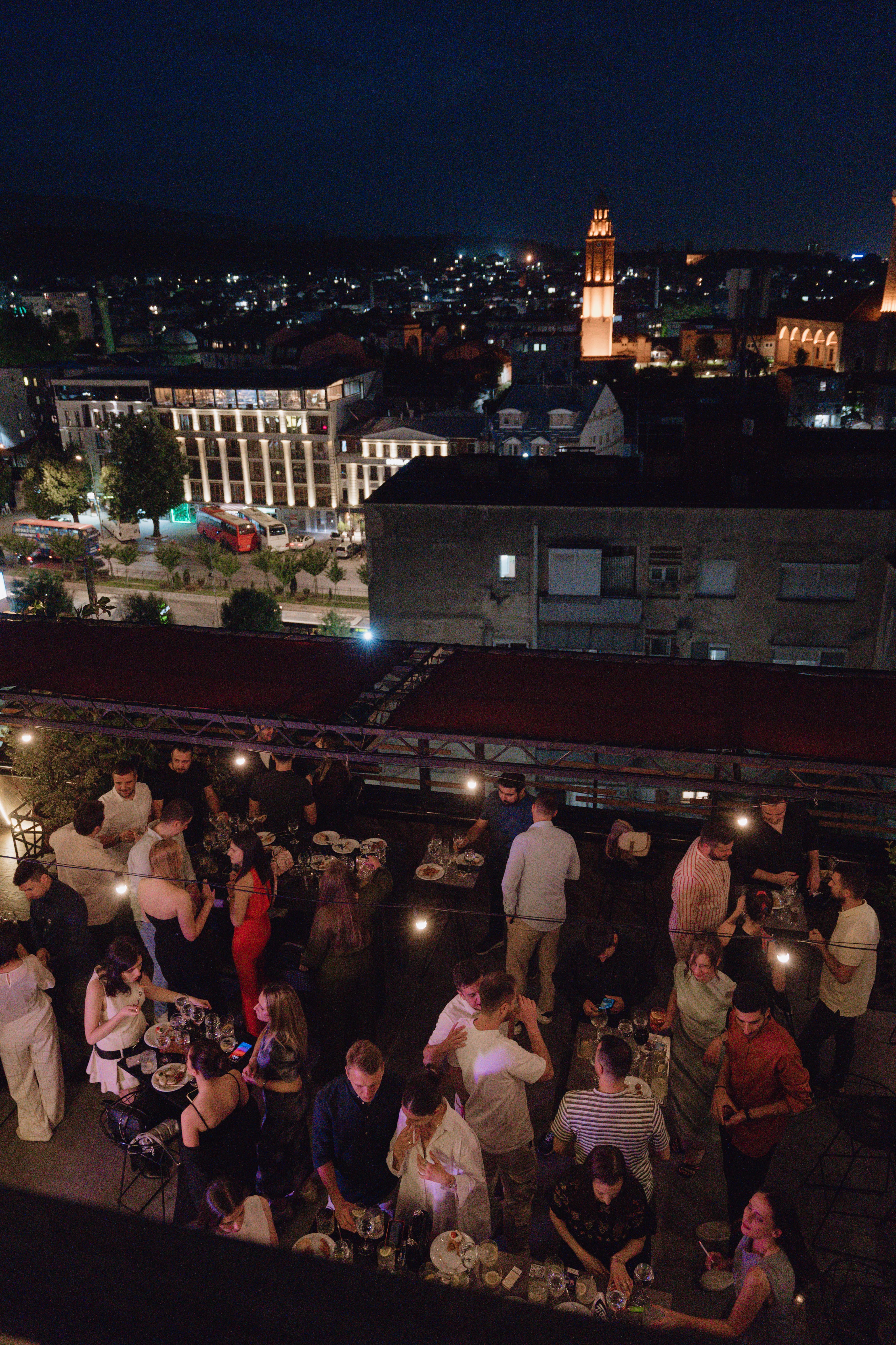 A lively gathering of people enjoying a party at a rooftop bar.