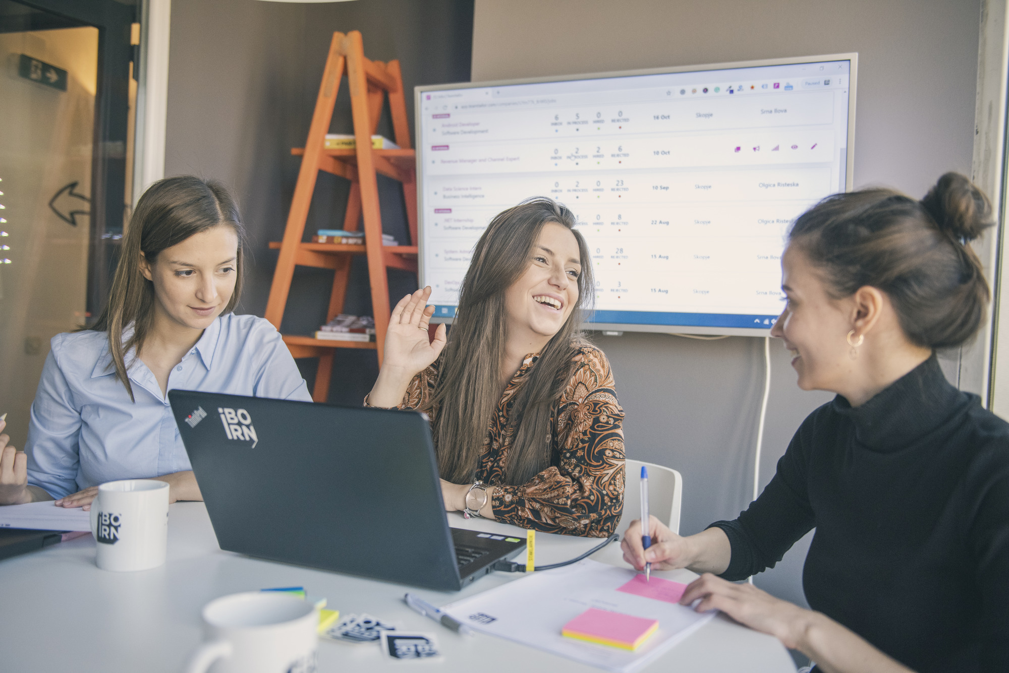 Three women having a collaborative workshop in a modern office environment.