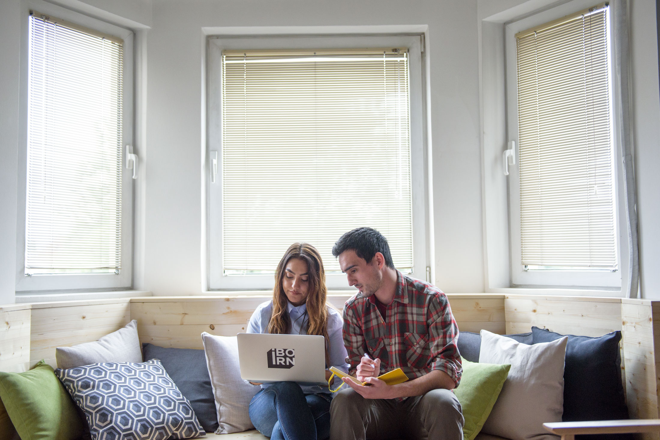 Two colleagues using a laptop while sitting on a couch.