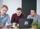 Three software engineers working together on a laptop in bright conference room.