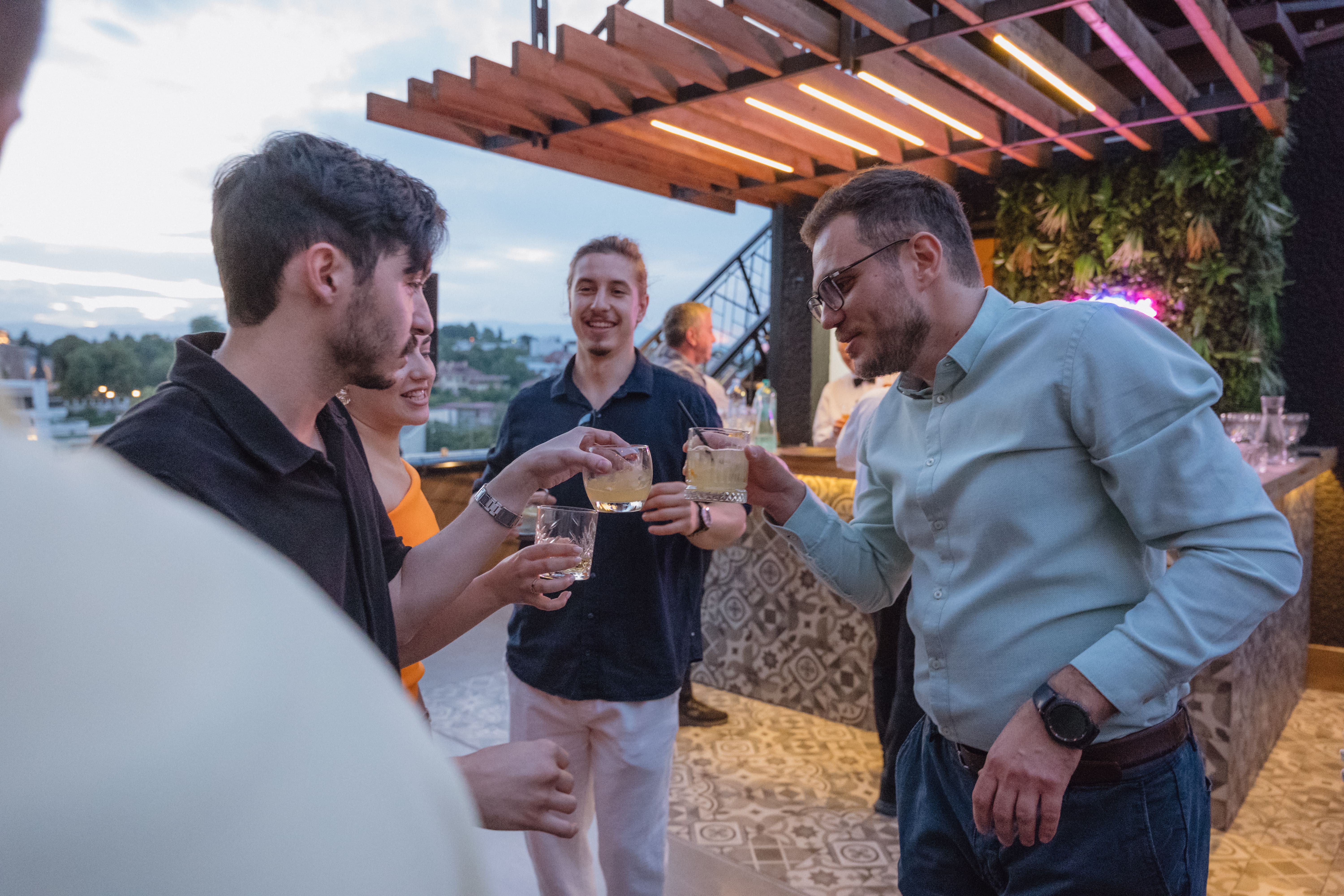 People celebrating on a rooftop, raising glasses in a toast.