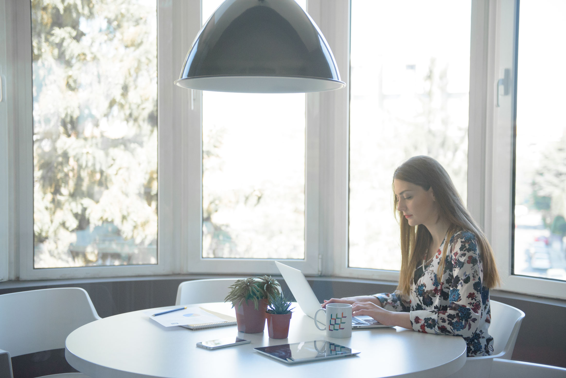 A woman sitting at a table, using a laptop for work.