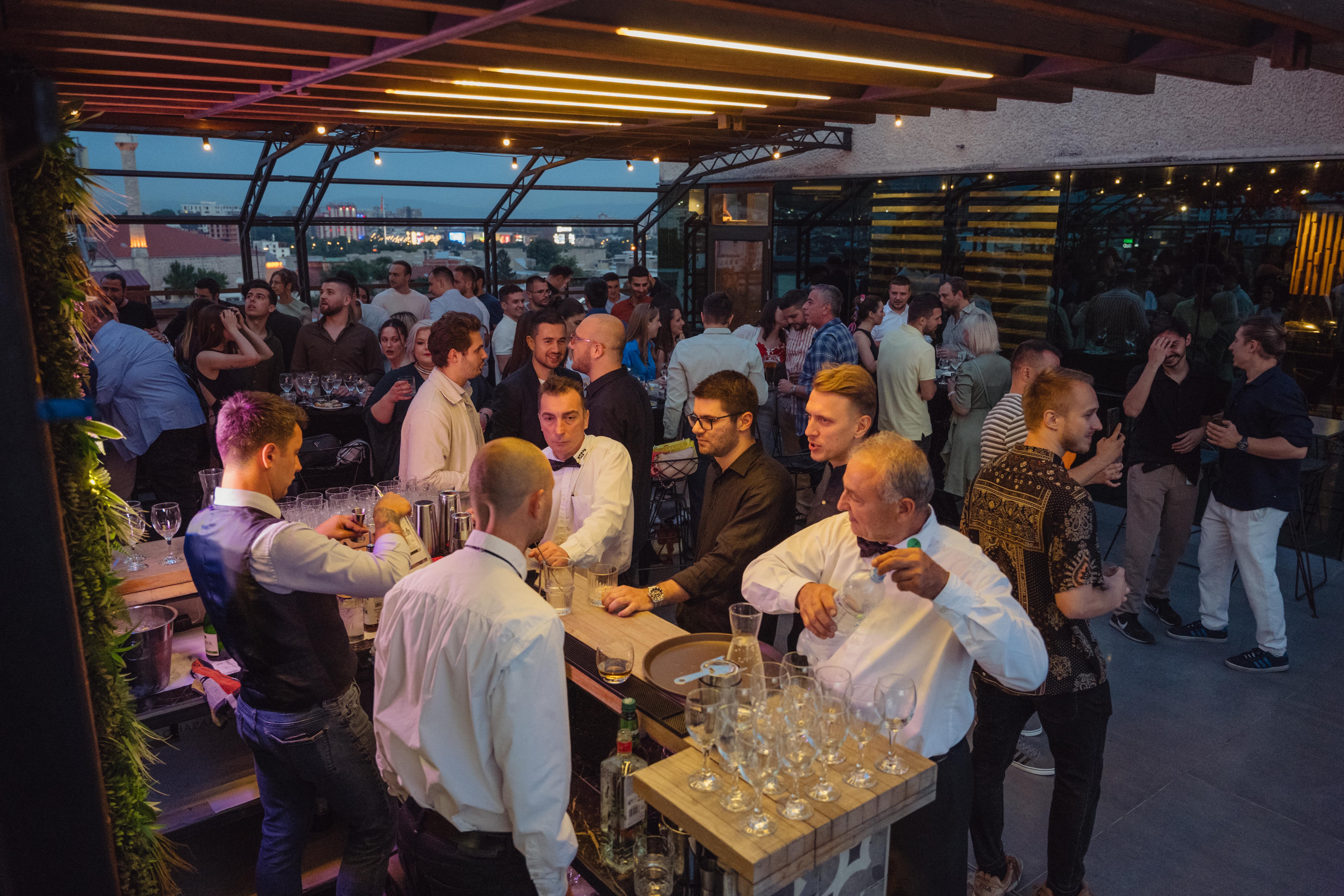 A group of people socializing at a bar, enjoying drinks and conversation in a lively atmosphere.