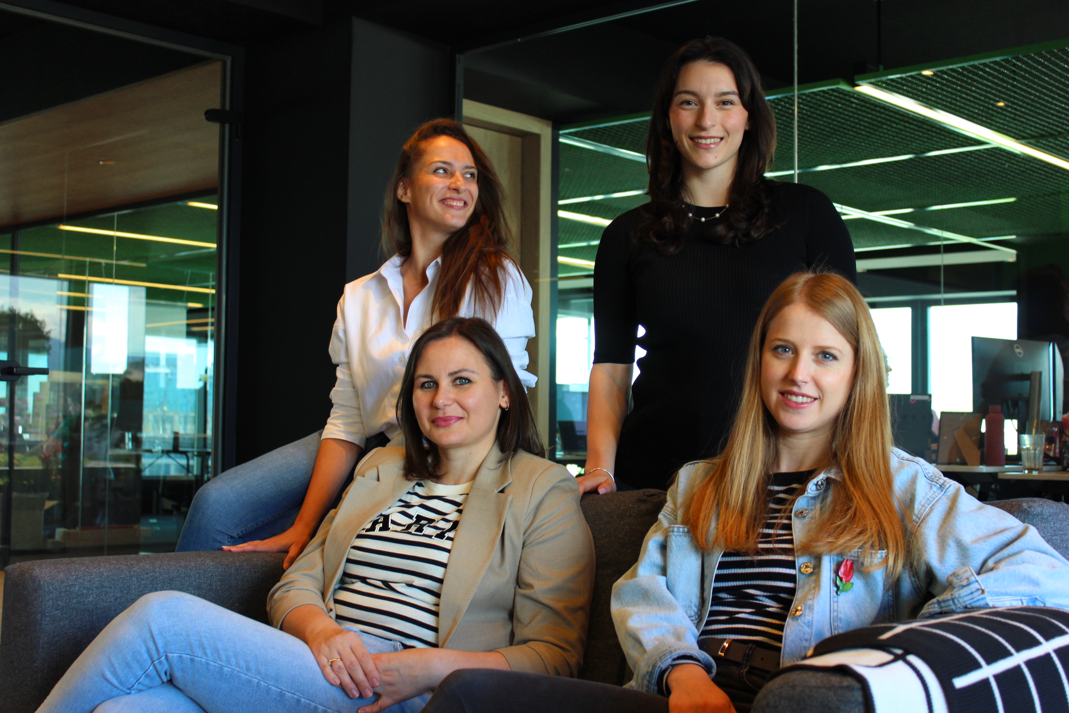 Women colleagues sitting together on a couch in an office.