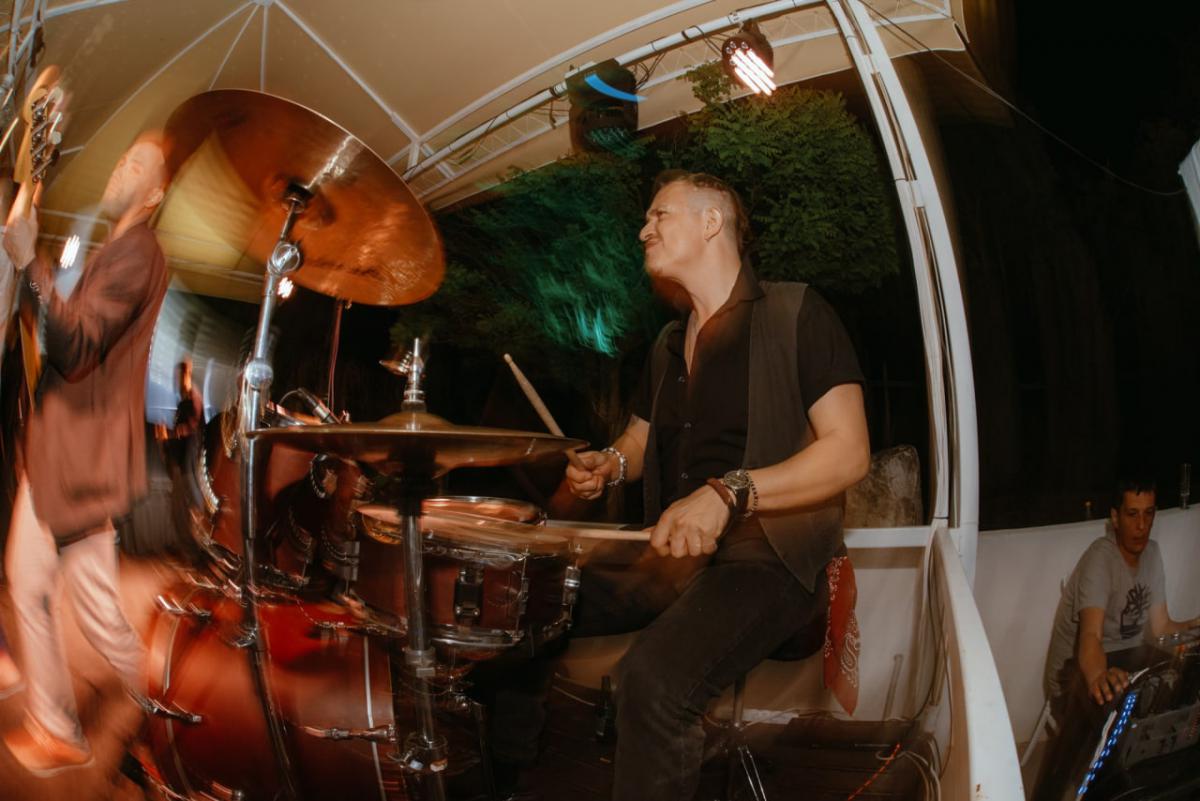 A man energetically playing drums at the founding anniversary party.