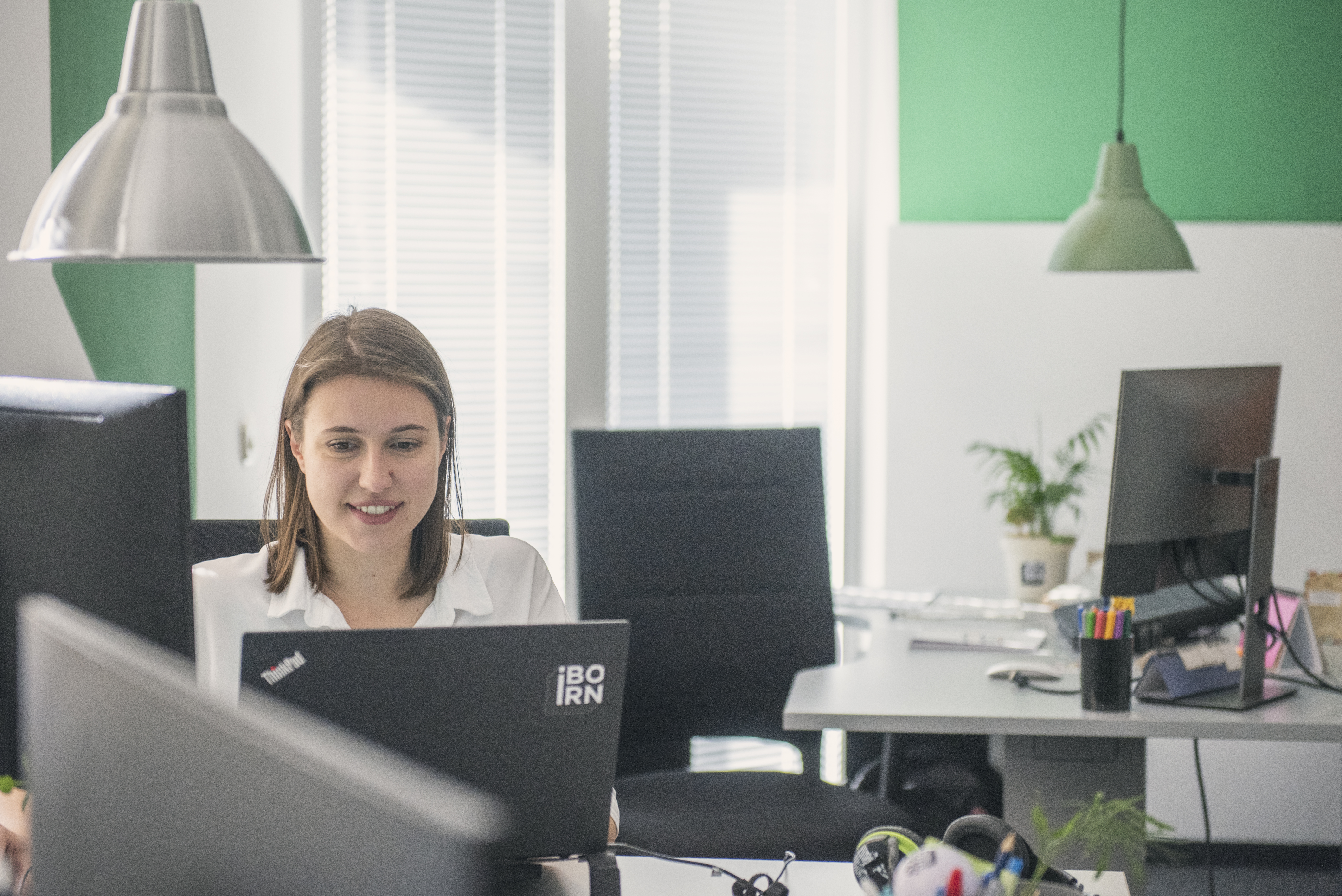 Software engineer working on her laptop with the IBORN logo on it. 