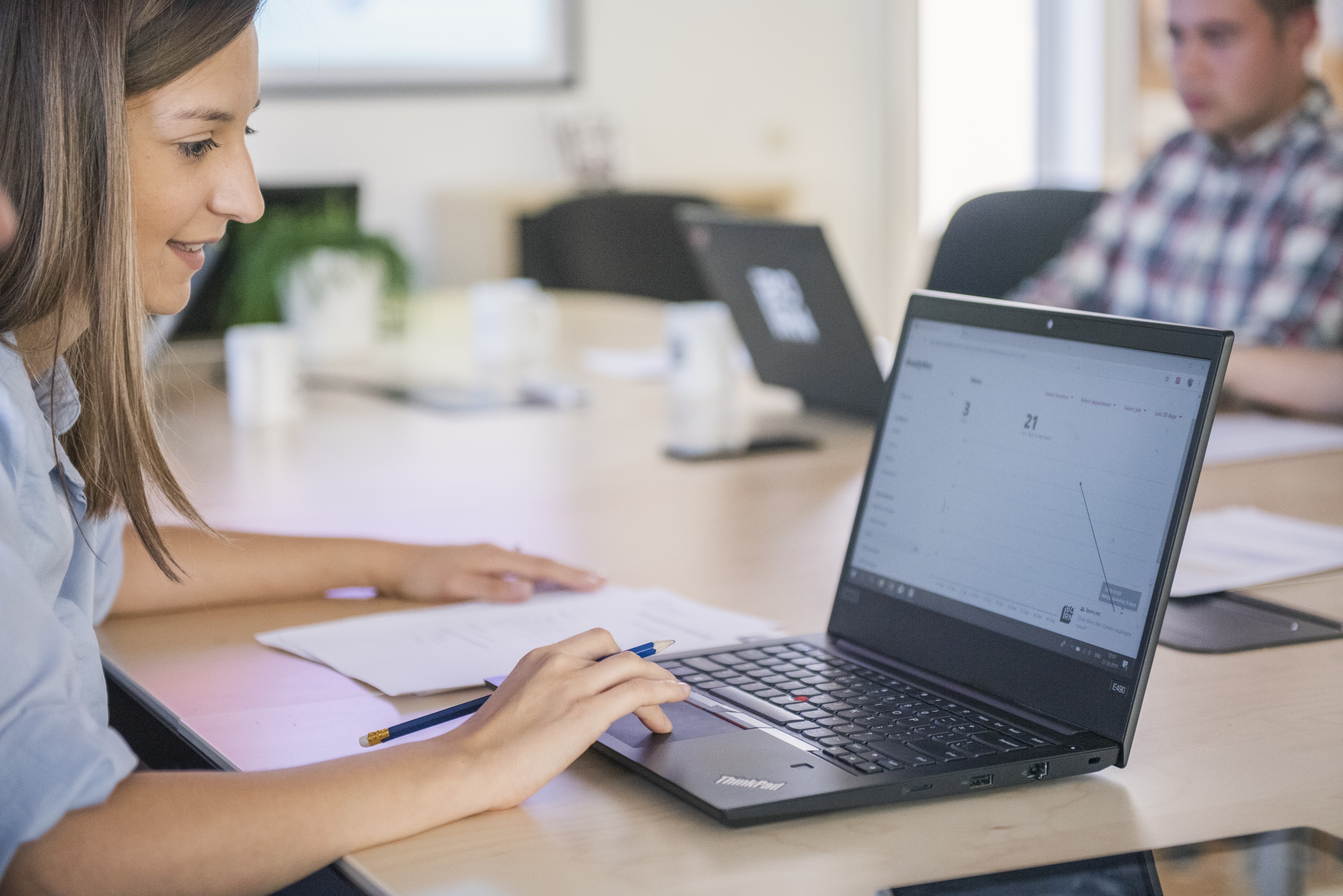A girl working on a laptop in a bright conference room. 