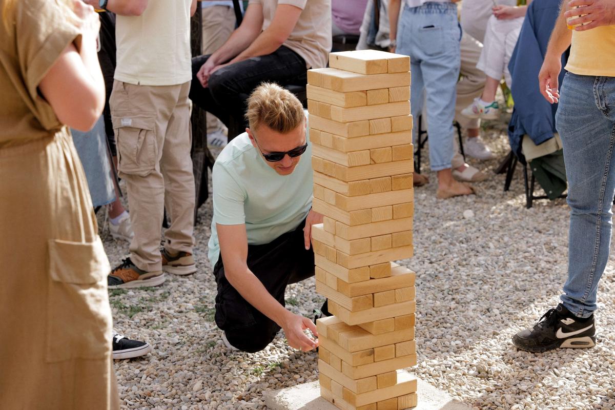 People playing Jenga during a sunny picnic founding anniversary party