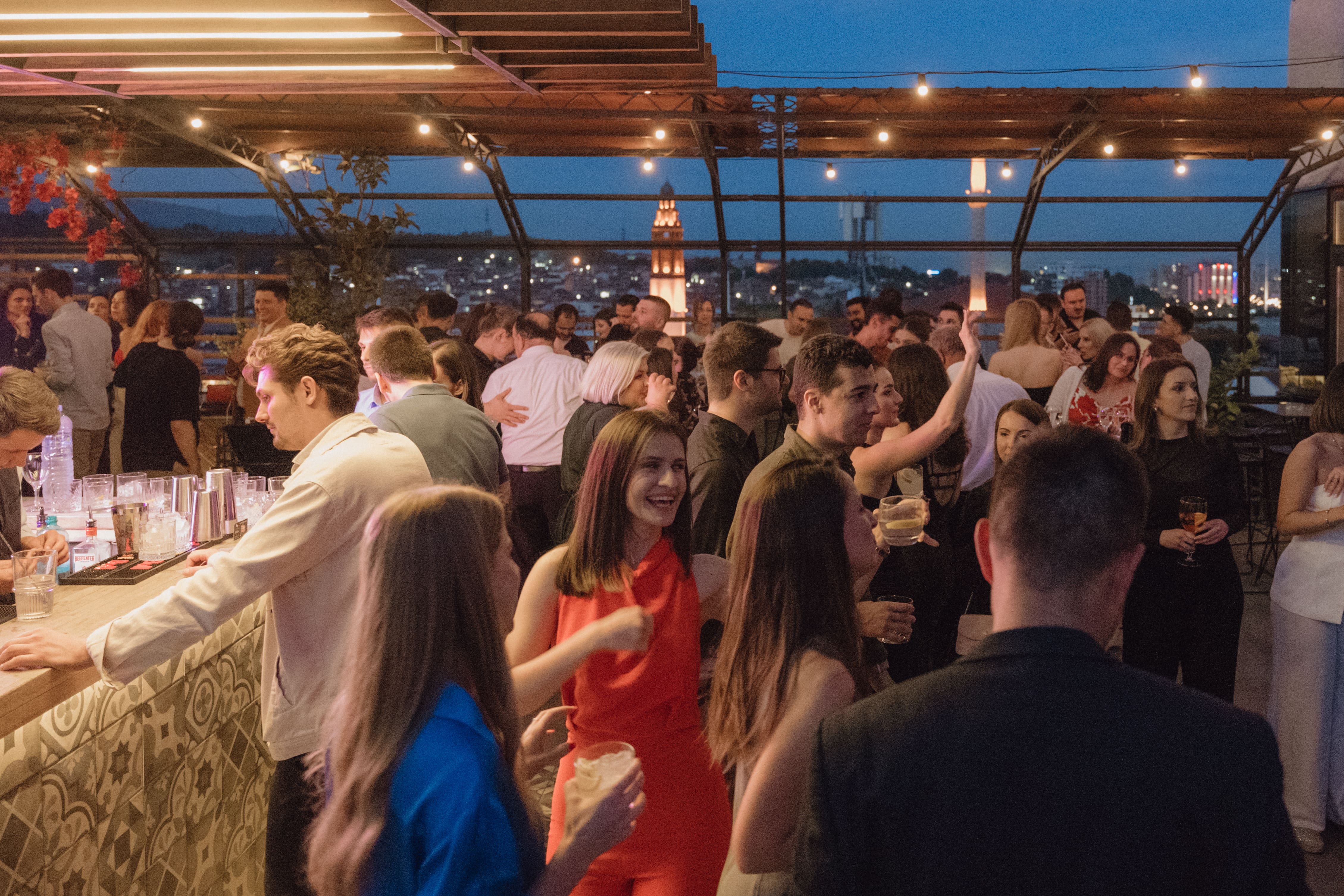 A lively rooftop party with a group of people enjoying themselves under the night sky.