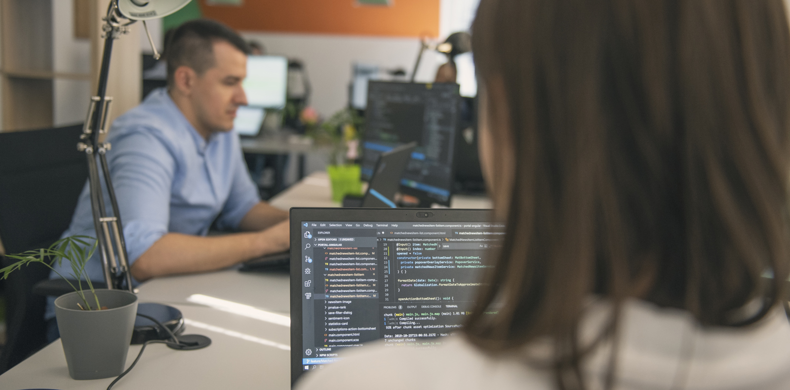 Software engineers working in a modern office, focused on the code on their screens. 