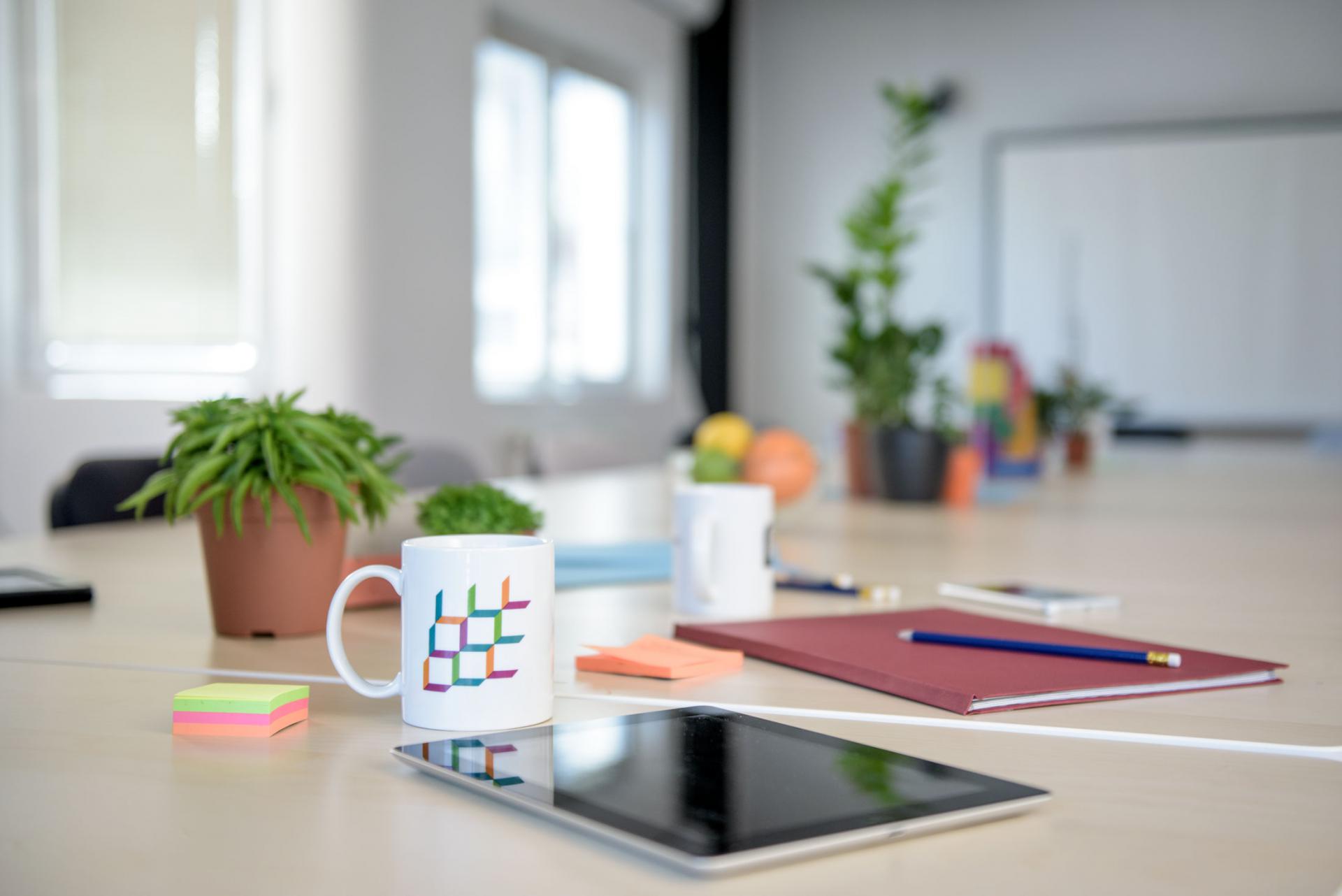 Various office supplies including a tablet, laptop, and coffee mug neatly arranged on a table.