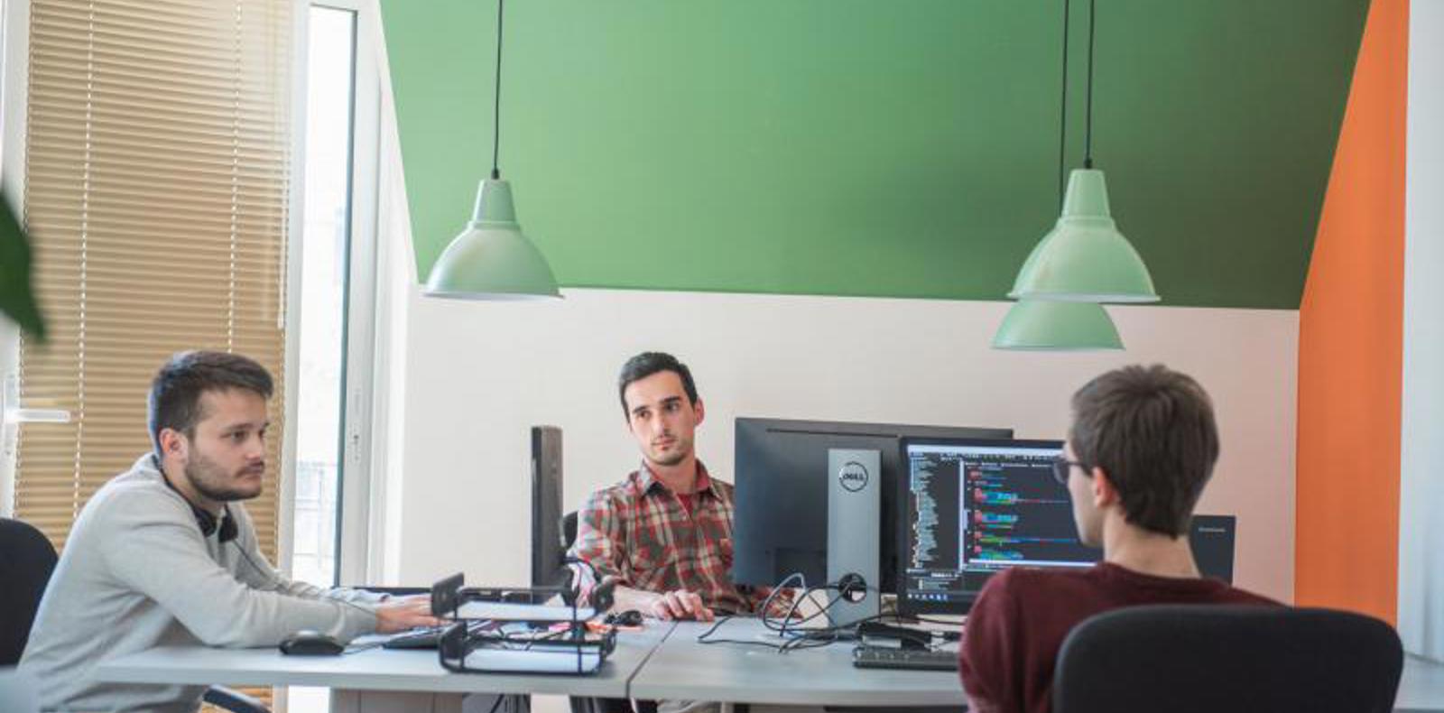 Three software engineers working together in a modern office environment.