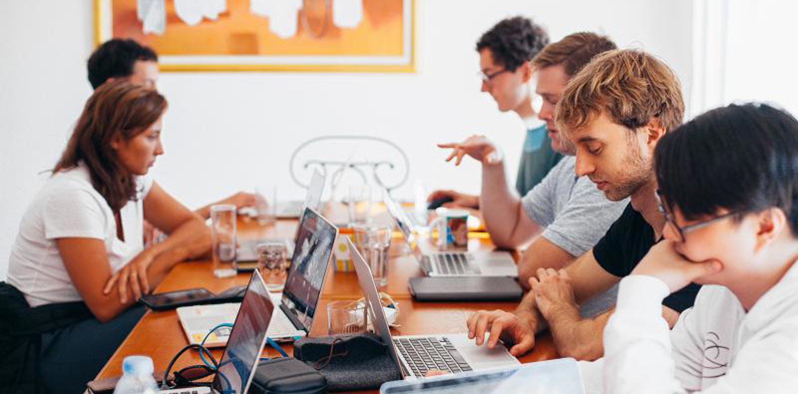 Diverse group of people working on their laptops n a conference room.