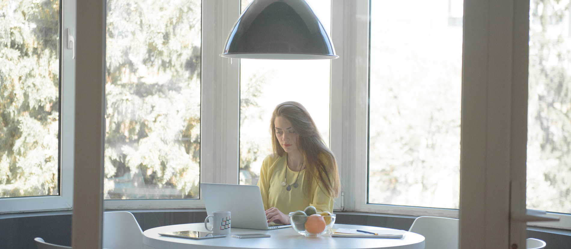 Three people collaborating at a table, focused on a laptop.