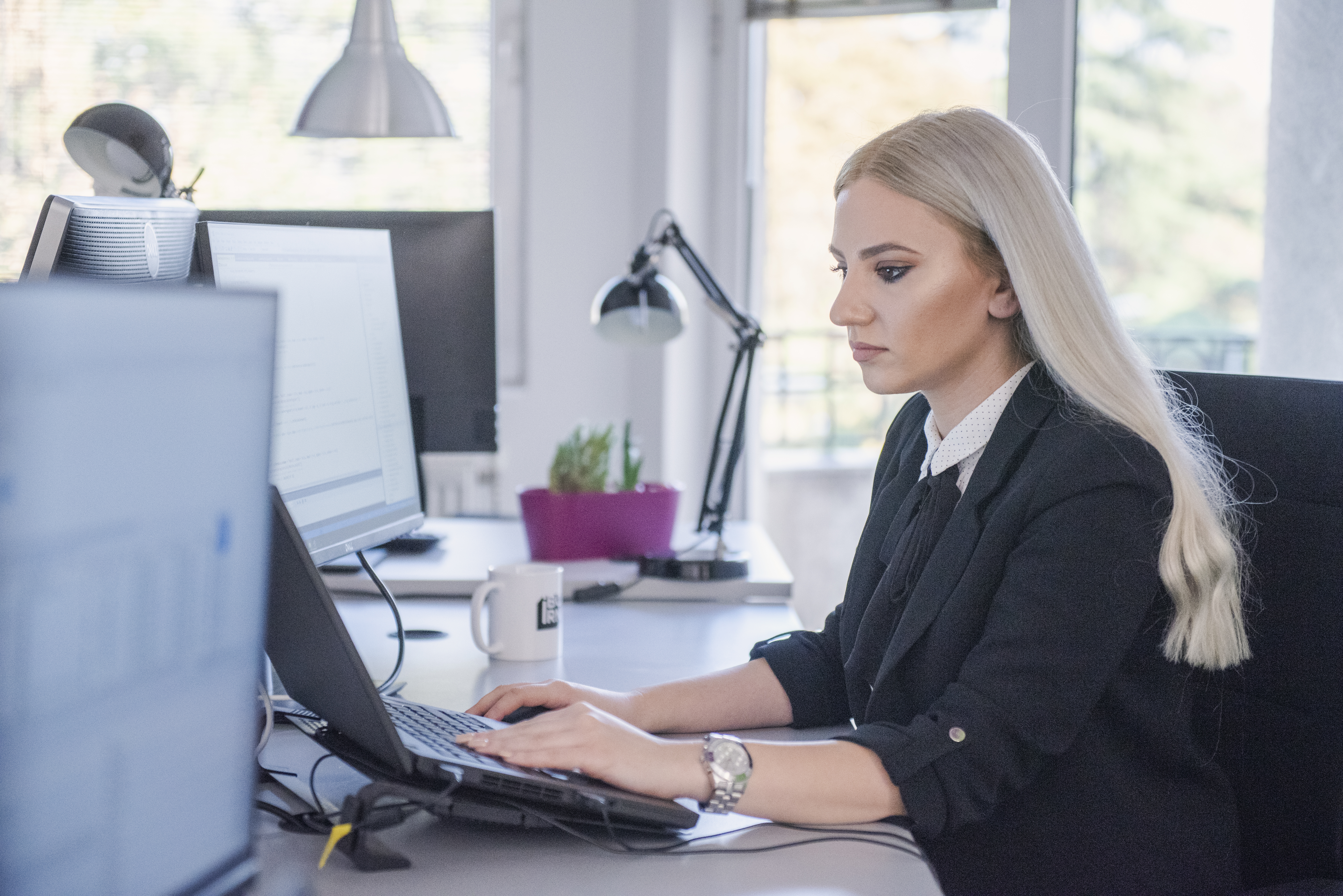Software engineer working on a laptop in a bright and modern office environment.